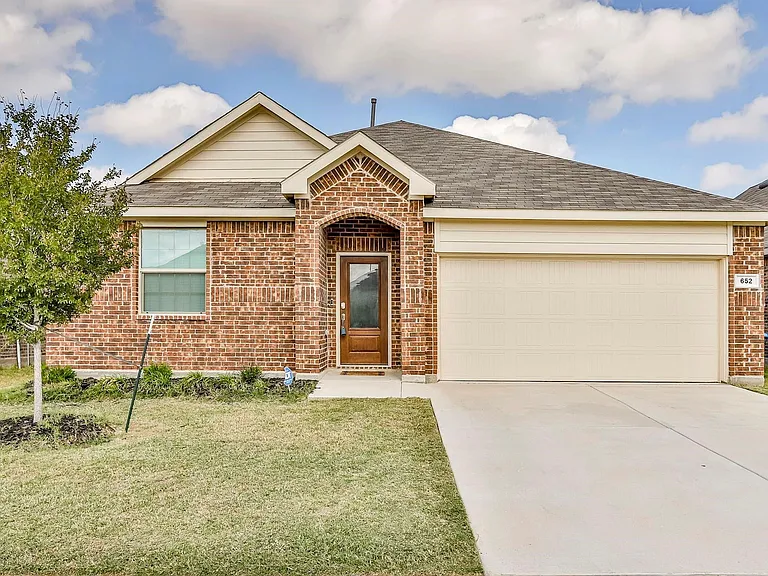 View of front facade featuring a garage and a front lawn