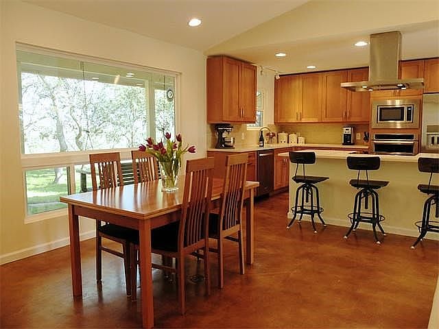 Large vaulted Great Room with windows and outdoor access on both sides of kitchen/living/dining area.