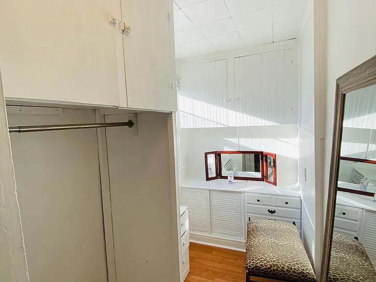 The bright large walk-in closet in the Third bedroom has a vanity, drawers, cabinets, and a clothes hanging rack.