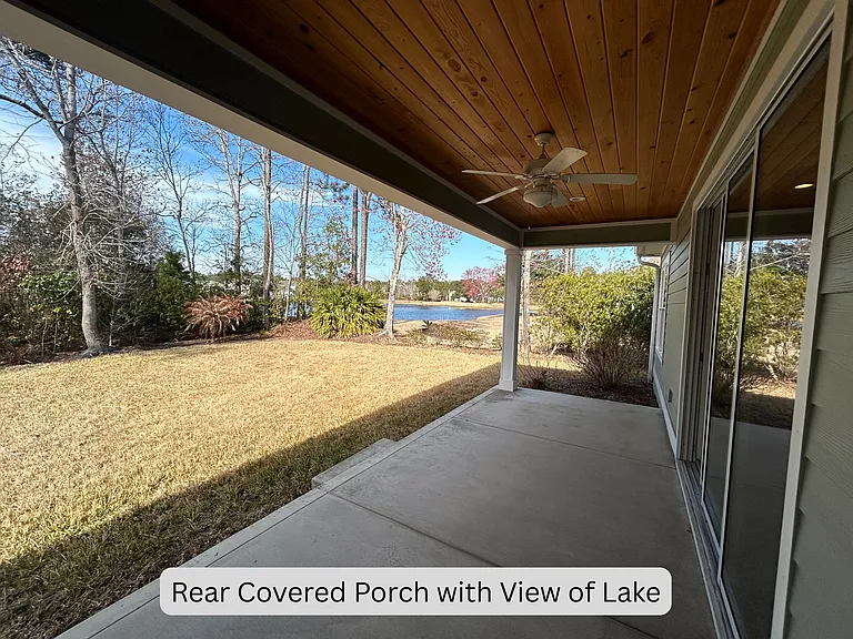 Rear covered porch with view of lake, with yard backing up to wooded preserve area