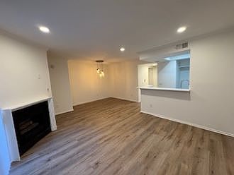 living area w/ fireplace, dining area under light fixture, open kitchen to the right