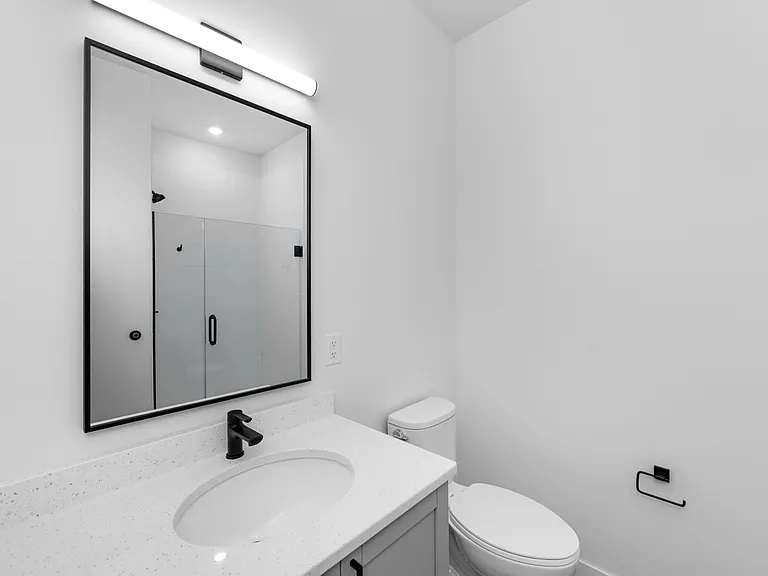 Modern bathroom design with sleek quartz countertop, elegant black fixtures, and a frameless glass shower. Modern bathroom design with sleek quartz countertop, elegant black fixtures, and a frameless glass shower.