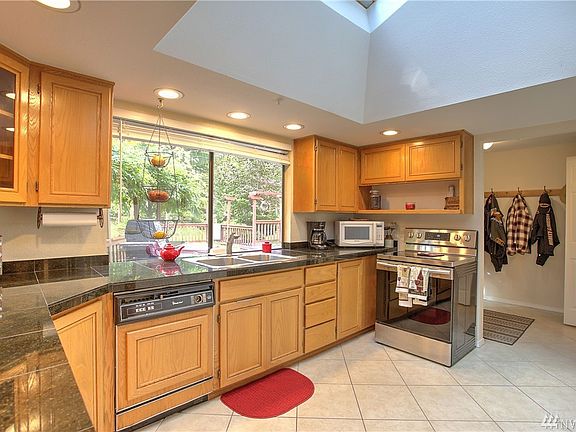 The kitchen offers granite tile countertops, tile flooring, quality oak cabinetry, recessed lighting, stainless steel appliances, a sizable closet-style pantry, recessed lighting and a huge skylight that opens.