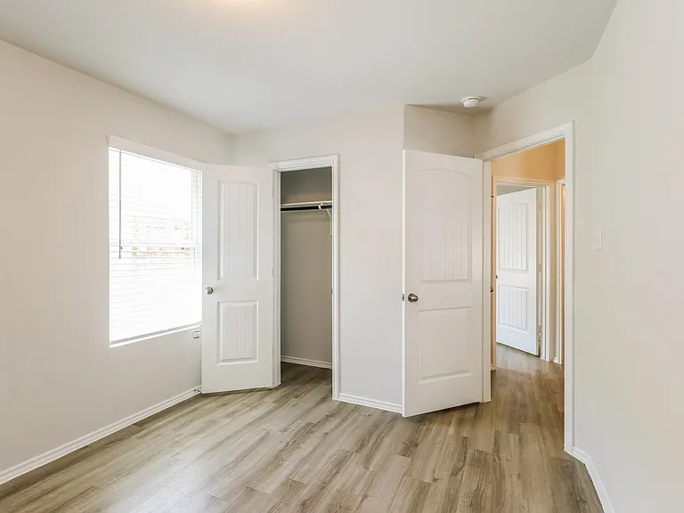 Bright and inviting room featuring elegant wooden flooring, a spacious closet, and ample natural light through a large window. Bright and inviting room featuring elegant wooden flooring, a spacious closet, and ample natural light through a large window.