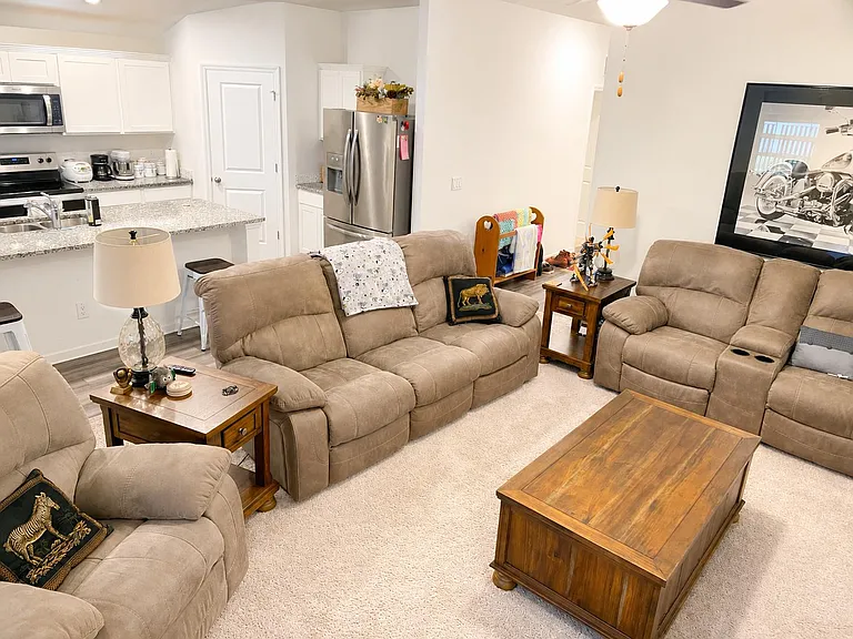 Open-concept living area with plush seating, soft carpeting, and quick access to the adjacent kitchen and breakfast bar.