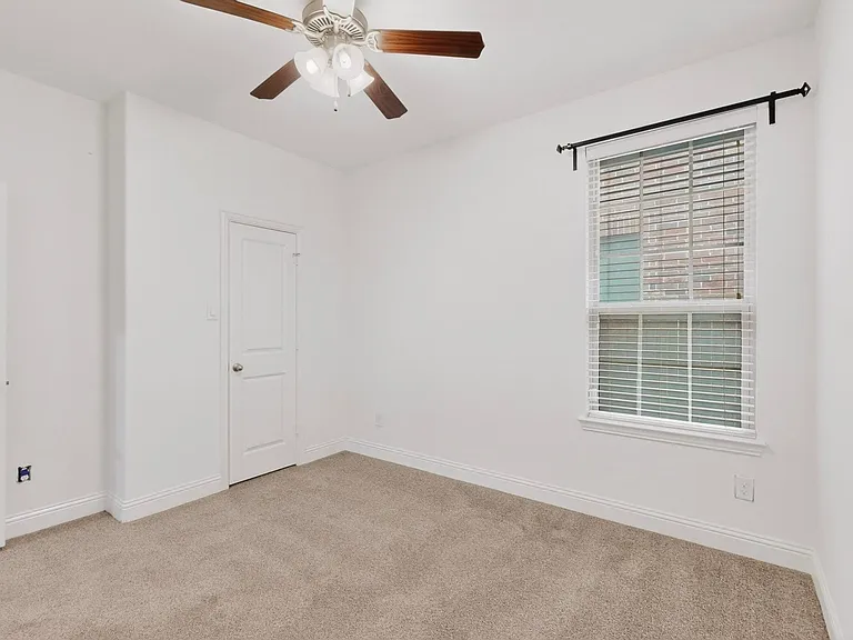 A bright bedroom featuring a ceiling fan, a window, and a walk-in closet