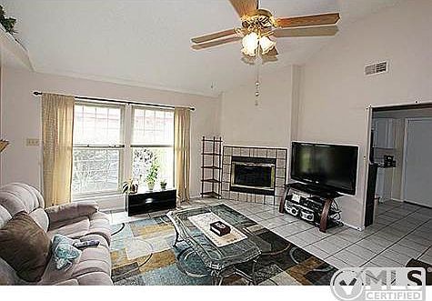 Spacious living room is cozy with a firpelace and ceiling fan.