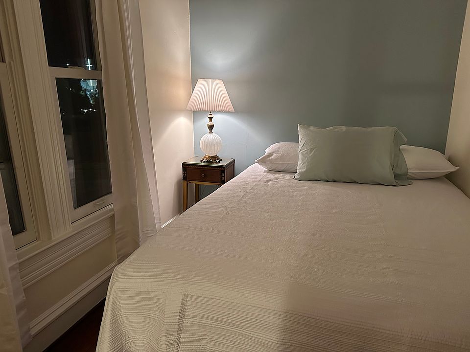 High quality newer mattress. The bedroom features an antique dresser, bedside table and lamp.