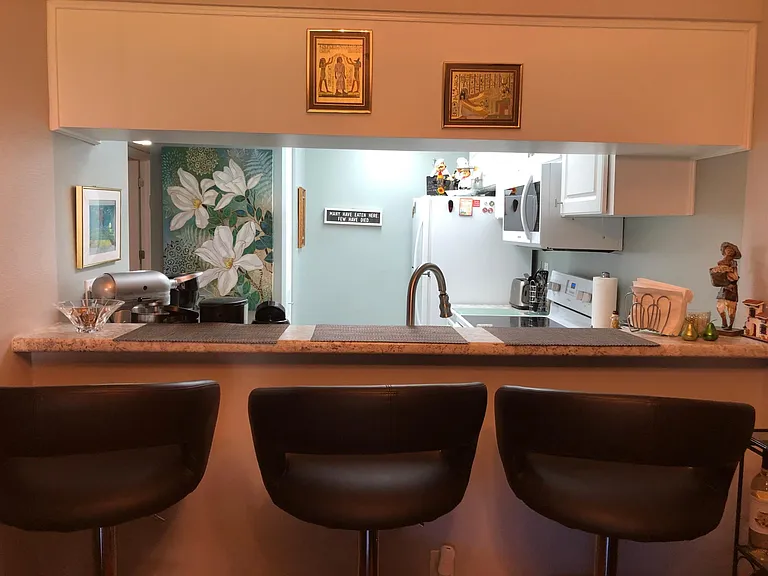 View to the kitchen from breakfast bar and dining room. Kitchen has stove, refrigerator, dishwasher, new microwave, and spacious pantry.