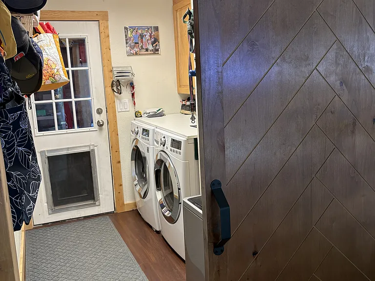 Closable barn door to laundry room with storage and dog door to enclosed yard