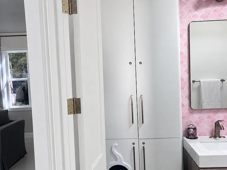 Thoughtfully designed bathroom storage includes extensive built-in cabinetry and a discreet cat-friendly litter-box cabinet with an adorable custom entryway.