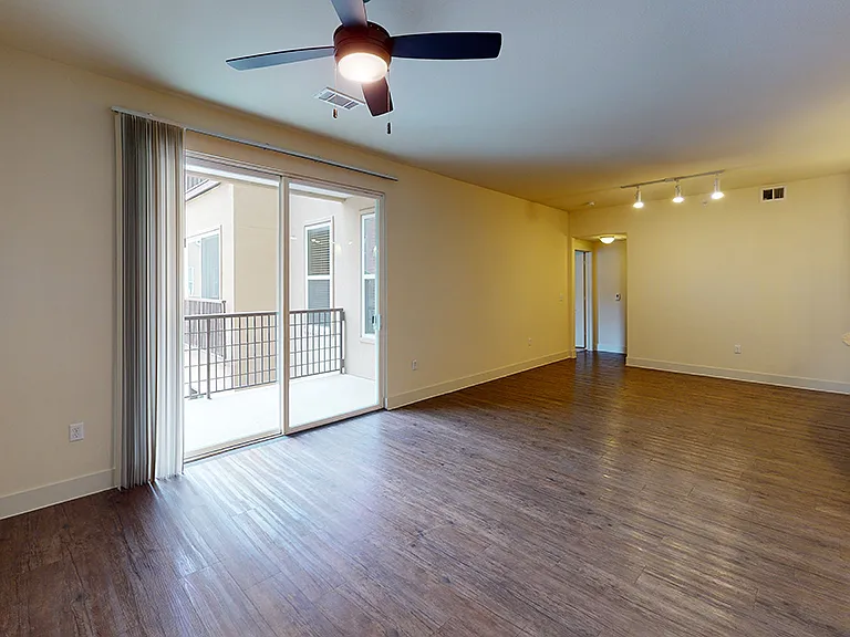 Apartment living room with wood-style flooring and balcony or patio in select homes.