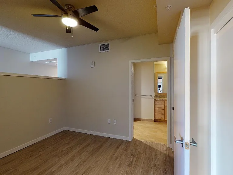 Spacious apartment bedroom with wood-style flooring.