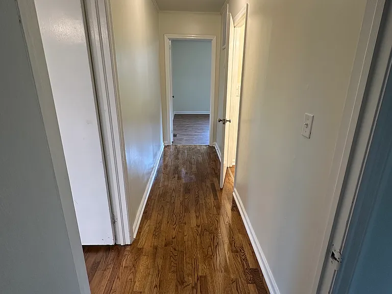 Hallway to main bedroom. Living room door on left. Bathroom door on right.