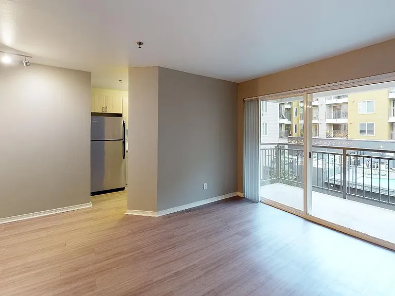 Apartment living room with wood-style flooring and balcony in select homes.