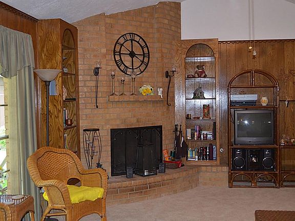 The family room has a brick fireplace and arched built-ins with plenty of shelving for books or more.