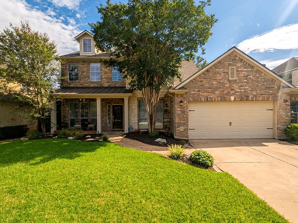 Classic two-story brick & stone elevation with mature shade tree and manicured lawn