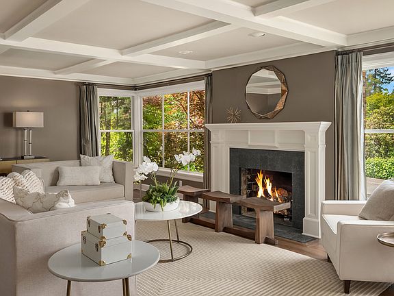 The living room..anchored by a beautiful wood burning fireplace, banks of windows let the sunshine stream in! Notice the handsome box-beamed ceiling.