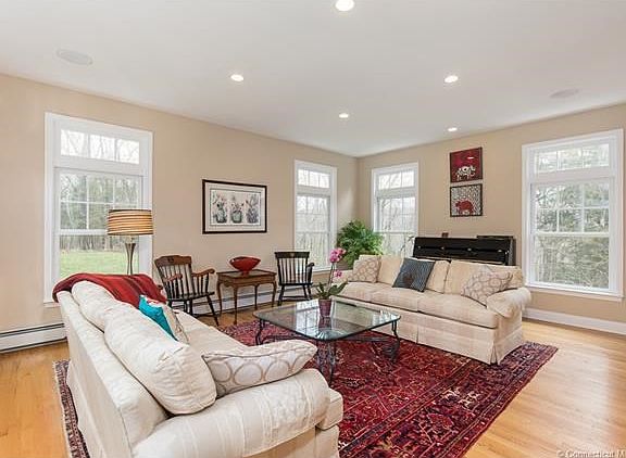 Living room with hardwood and oversized windows has beautiful views of private and picturesque property.