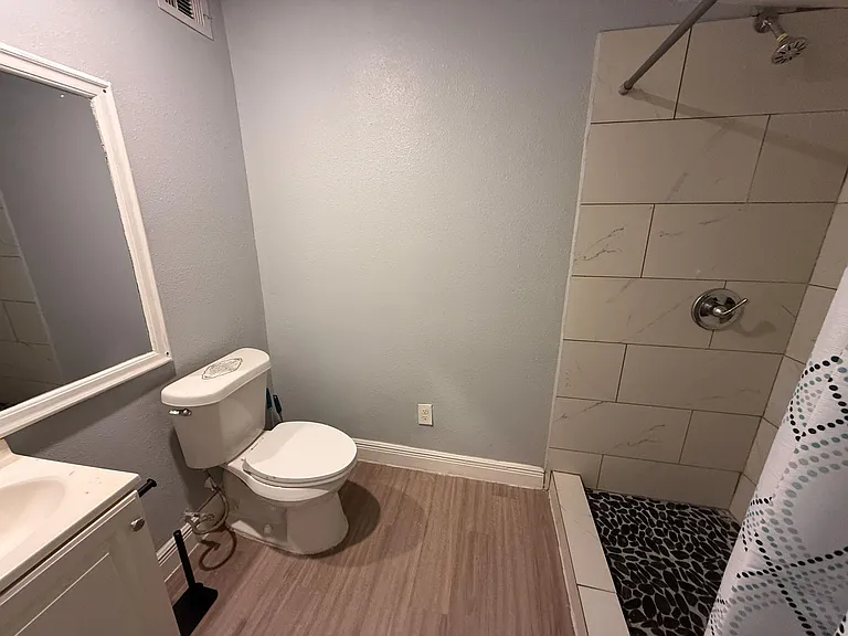 Full bathroom featuring a tiled shower/tub combo, vanity storage, and easy-care flooring for everyday convenience.