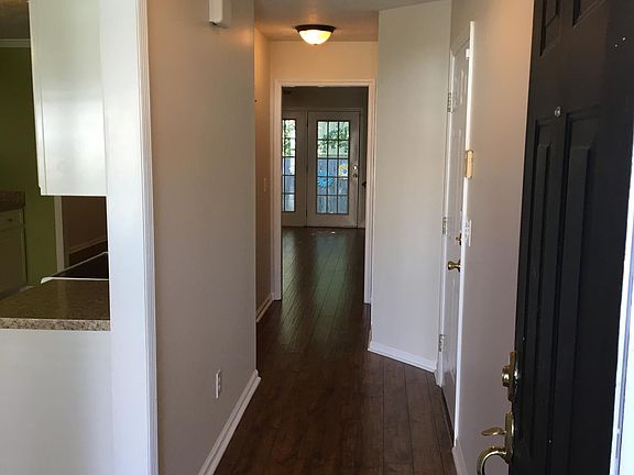 Entry with wood floors continuing into living room. Kitchen is on the left.