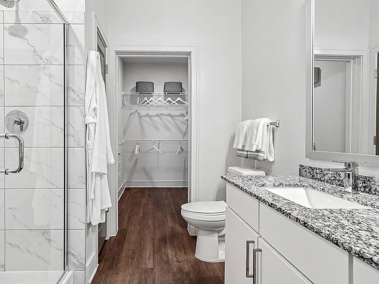 Bath with white cabinetry, speckled granite countertops, and hard surface flooring