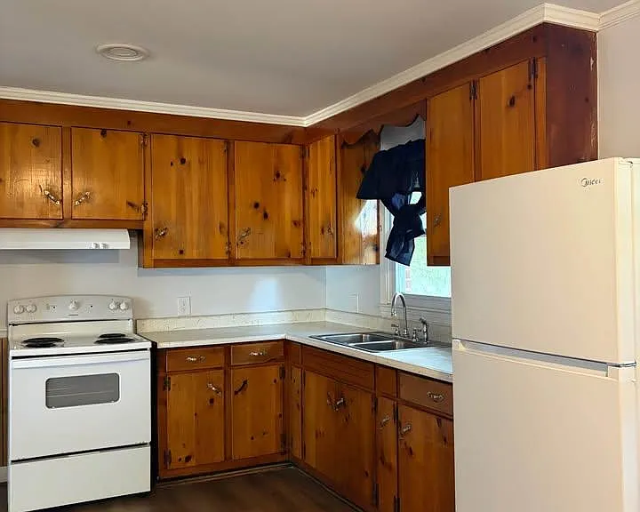 U-shaped kitchen with wood cabinetry, laminate countertops, double-basin sink, and a full appliance set for daily cooking.