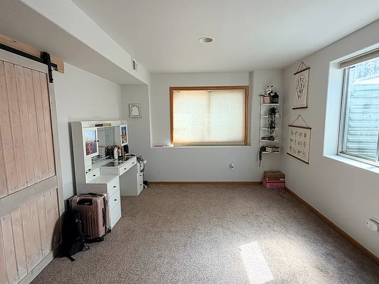 Bedroom #4 with sliding barndoor, carpeted, large window for views outside and window well window, tall ceilings