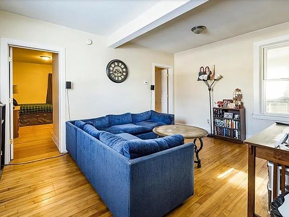Living room with original hardwood floor with wide windows drawing nautral light.