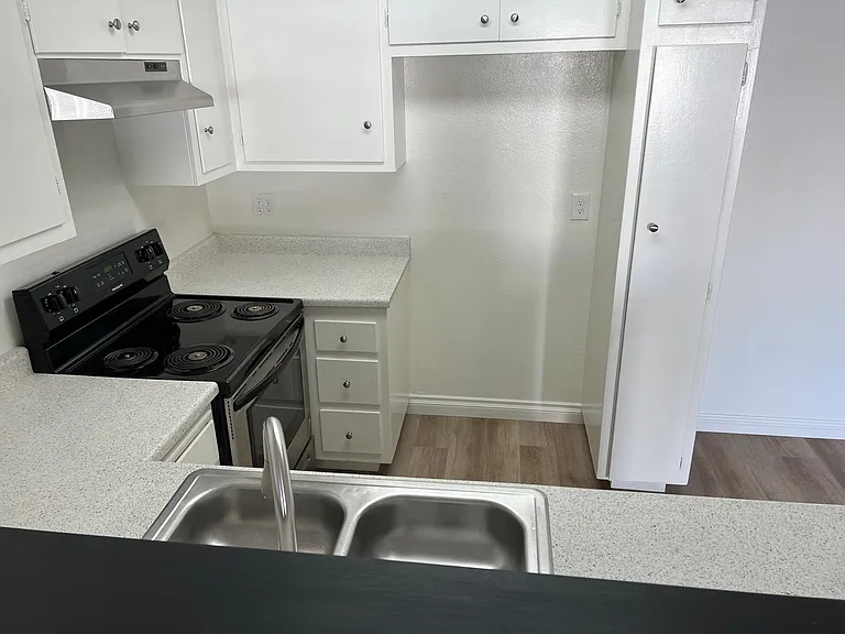 Standing in the living room area looking through the cut out counter doward refrigerator opening. 2x2