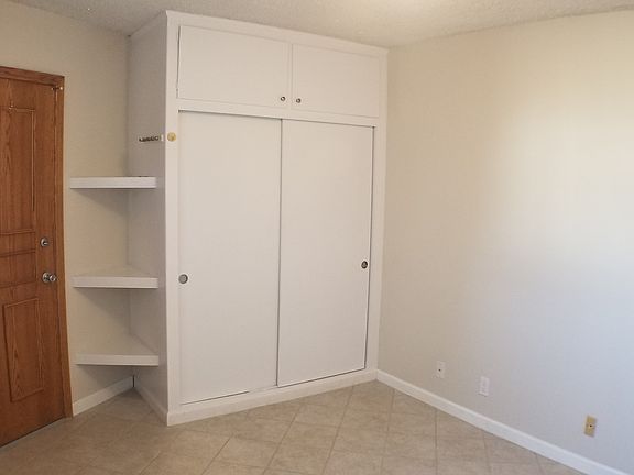 Large closet with storage cabinets above and built in bookcase to side