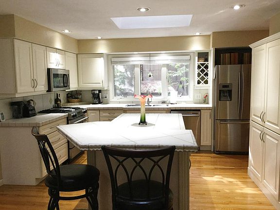 The kitchen has plenty of space and cabinetry along with large island with seating, stainless steel appliances including gas stove and brand new microwave,  solid hardwood flooring and skylight.  The half bath is just around the corner for convenience too.  
