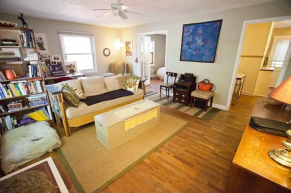 Furnished living room with access to kitchen and its eating nook and double doors to the bedroom.
