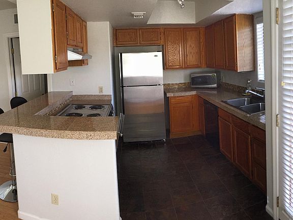 Kitchen with slate tiles, granite tile counters, dishwasher, microwave, and stainless refrigerator & stove.