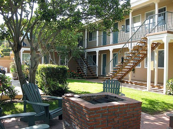 BBQ area surrounded by adirondack chairs in the grass area.