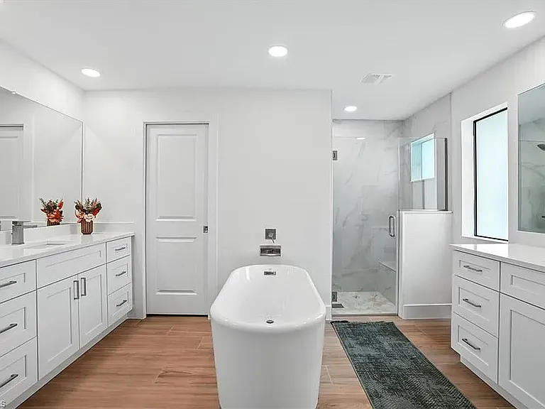 Primary bathroom with dual walk-in closets, vanities and free standing tub.