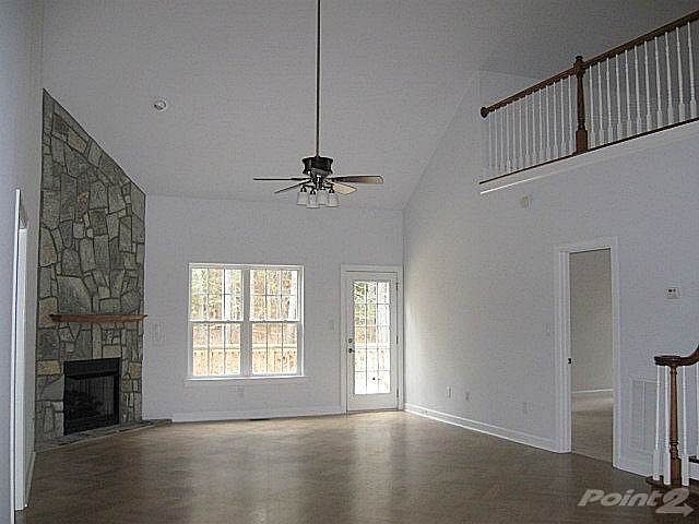 Oh so spacious living room features gas-log fireplace with stone surround and French door to deck. Door at right is to master bedroom.