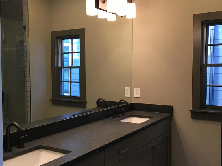 Upstairs primary bathroom with shower and vanity with two sinks.