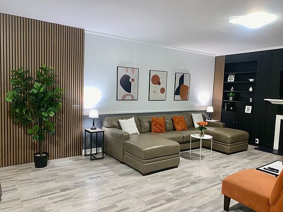 Modern open-plan living room with a stylish leather sofa that pulls out into a full-size bed, flat-screen TV, and plenty of space to relax or entertain.