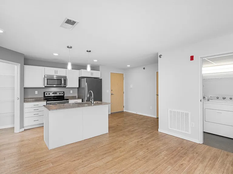 Modern open-concept kitchen and living area with sleek appliances, hardwood flooring, and convenient in-unit laundry. Modern open-concept kitchen and living area with sleek appliances, hardwood flooring, and convenient in-unit laundry.