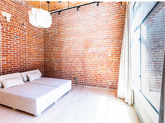 Fully enclosed bedroom features large window, closet, and 2 original brick walls from 1917 warehouse.