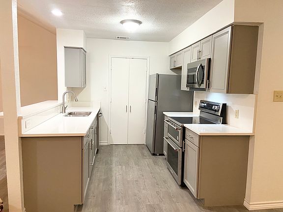 Galley style kitchen with stainless steel applicances: dishwasher, refrigerator, microwave and