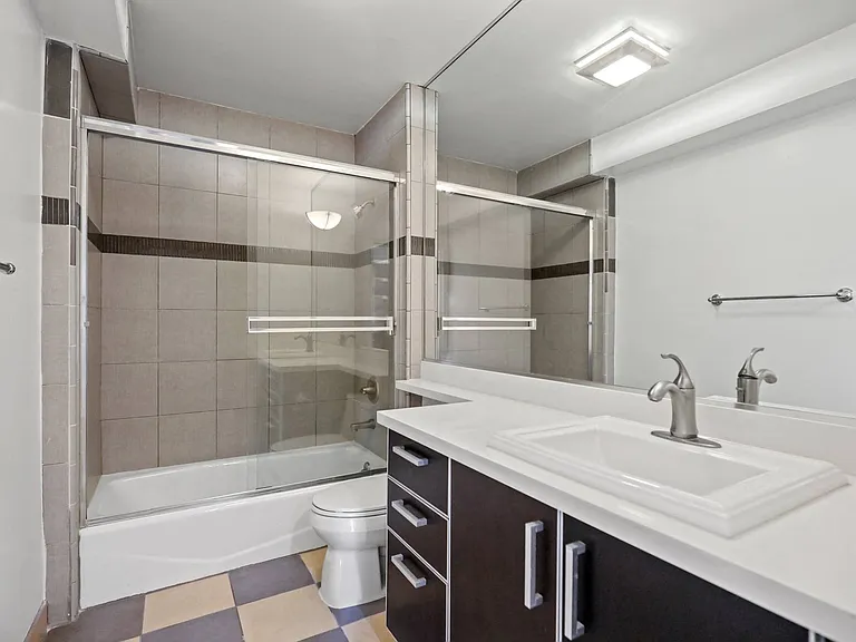 Bathroom with Bathtub with Glass Doors and Cabinet Storage