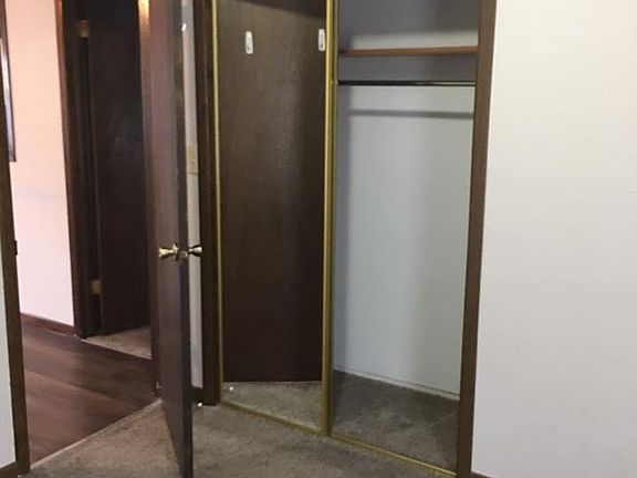 Bedroom #1 with glass sliding door closet. View to living room & doorway to 2nd bedroom.