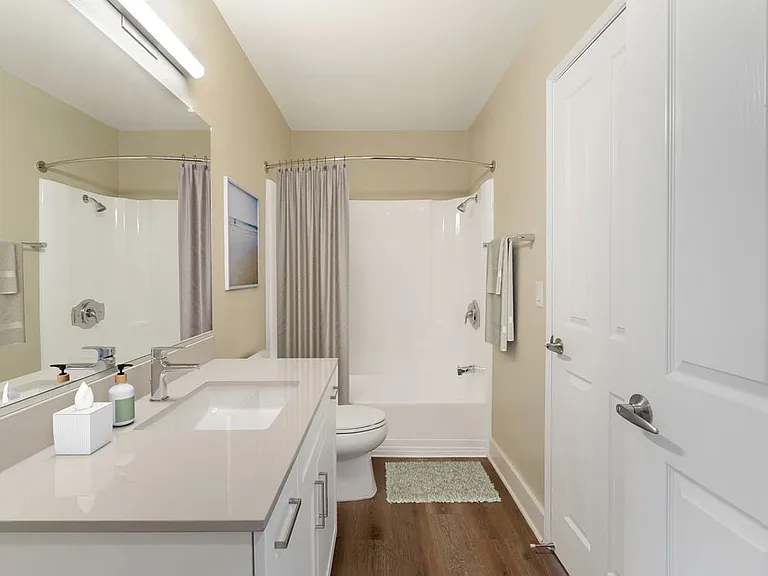 Renovated Package I bath with beige granite countertops, white cabinetry, and hard surface flooring