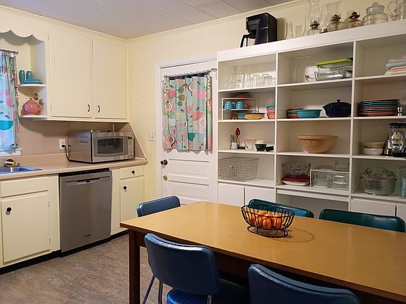 Kitchen has stove, fridge, microwave, dishwasher, and open shelving.