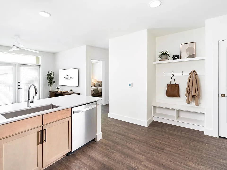 Open kitchen and living area with a central island, light wood cabinetry, and a built-in entry drop zone that keeps daily essentials organized.