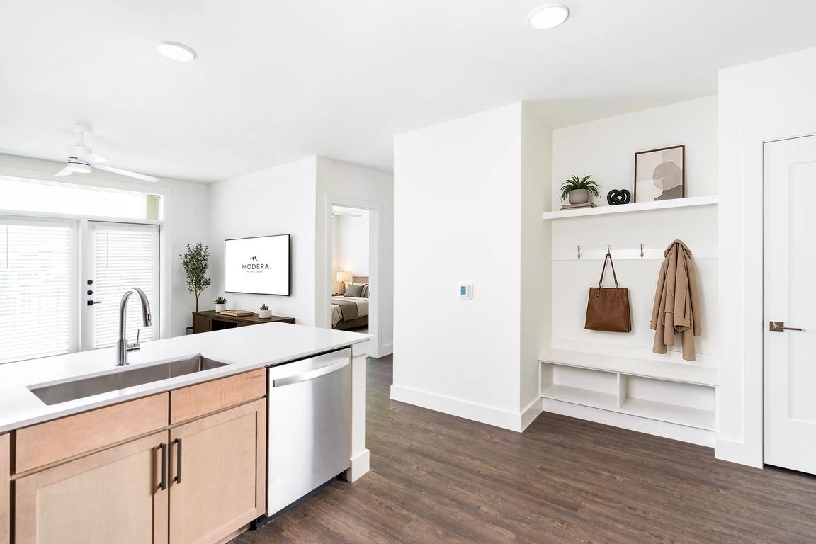 Open kitchen and living area with a central island, light wood cabinetry, and a built-in entry drop zone that keeps daily essentials organized.