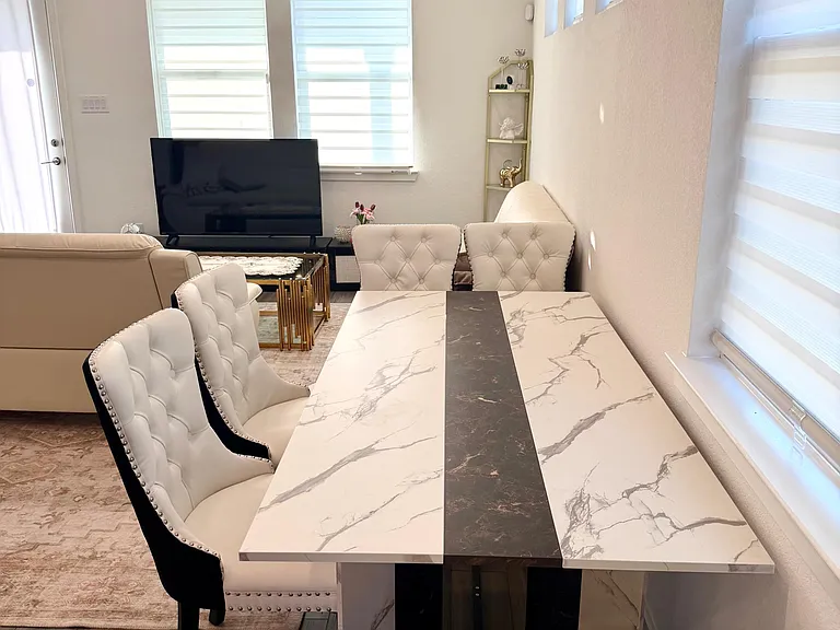 Dedicated dining area with a marble-look table, upholstered seating, and quick access to the adjoining living space.