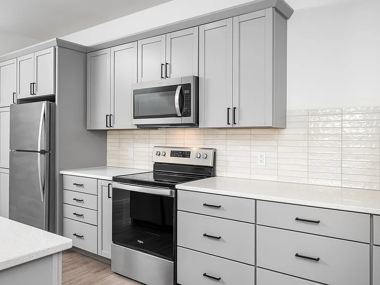 Modern kitchen with sleek gray cabinetry, stainless steel appliances, and elegant tile backsplash. Modern kitchen with sleek gray cabinetry, stainless steel appliances, and elegant tile backsplash.